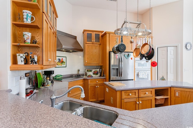 kitchen featuring appliances with stainless steel finishes, tasteful backsplash, wall chimney exhaust hood, light stone countertops, and sink