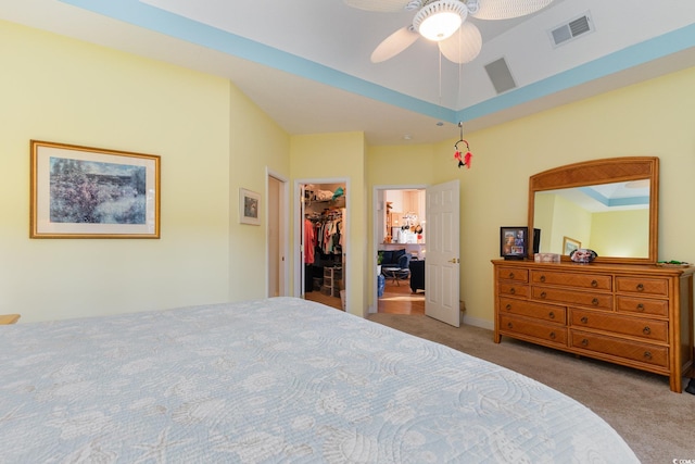 bedroom featuring a spacious closet, a closet, ceiling fan, and light carpet