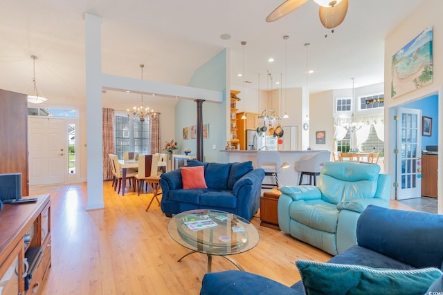 living room featuring ceiling fan with notable chandelier, light hardwood / wood-style floors, and a wealth of natural light