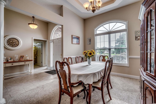 carpeted dining space with a textured ceiling, a healthy amount of sunlight, an inviting chandelier, and ornate columns