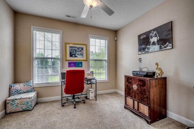 carpeted home office with a textured ceiling, ceiling fan, and plenty of natural light