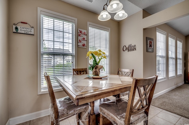 tiled dining room featuring a textured ceiling, a notable chandelier, and a wealth of natural light