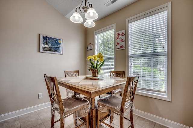 tiled dining space with a textured ceiling and a notable chandelier