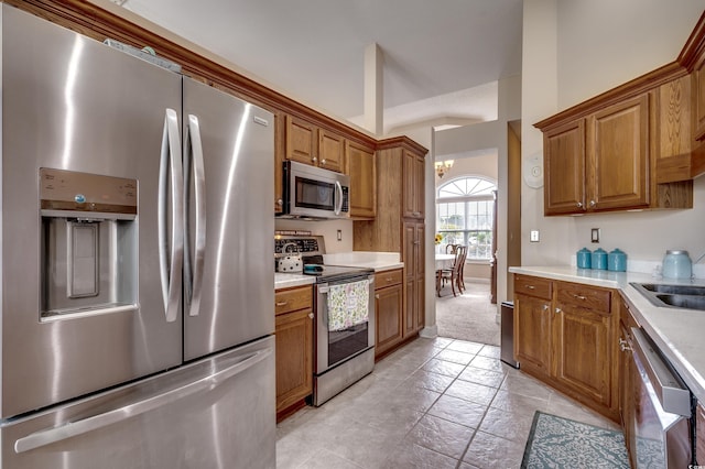 kitchen featuring a high ceiling, light carpet, stainless steel appliances, and a notable chandelier