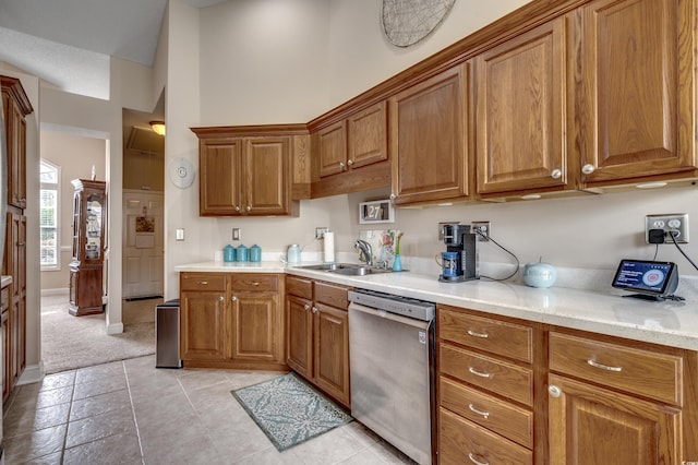 kitchen with light tile patterned floors, light stone countertops, sink, and stainless steel dishwasher