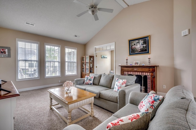 living room with ceiling fan, a textured ceiling, high vaulted ceiling, light colored carpet, and a fireplace