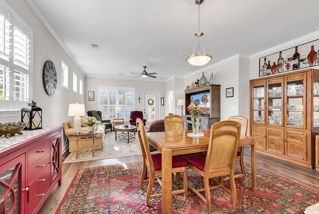 dining space featuring crown molding, ceiling fan, and dark wood-type flooring