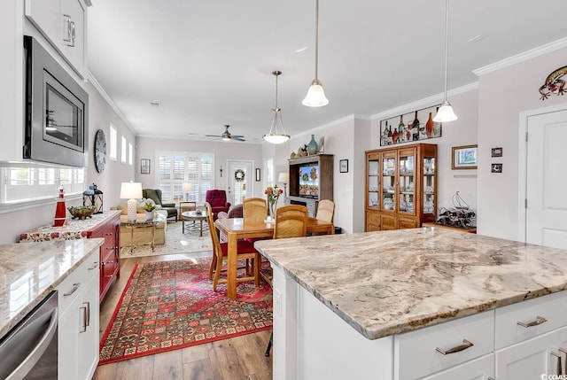 kitchen featuring white cabinets, light hardwood / wood-style flooring, decorative light fixtures, crown molding, and ceiling fan