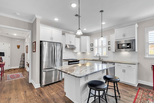 kitchen with stainless steel appliances, a center island, dark wood-type flooring, and a healthy amount of sunlight