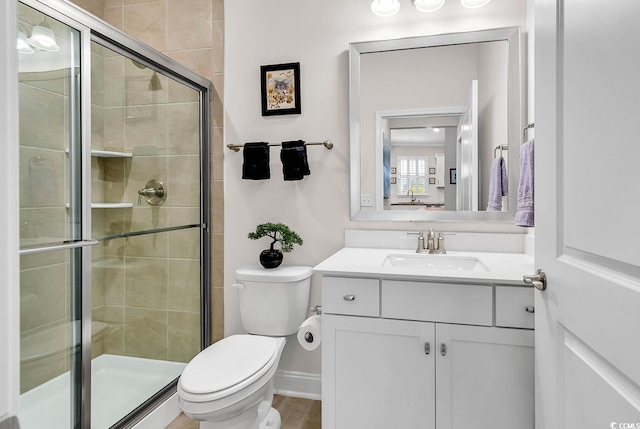 bathroom featuring vanity, toilet, and a shower with door