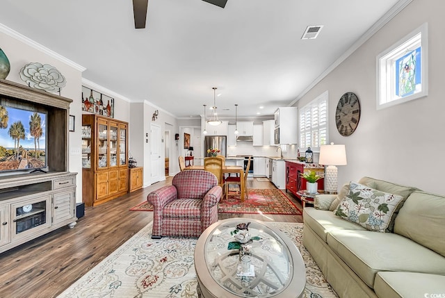 living room with ceiling fan, dark hardwood / wood-style floors, sink, and crown molding