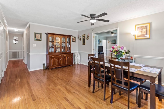 dining space with light wood-type flooring, a textured ceiling, ceiling fan, and crown molding