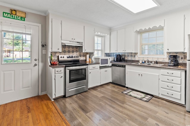 kitchen featuring appliances with stainless steel finishes, sink, white cabinetry, and light hardwood / wood-style flooring