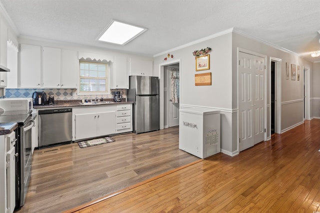 kitchen with appliances with stainless steel finishes, backsplash, light wood-type flooring, crown molding, and sink