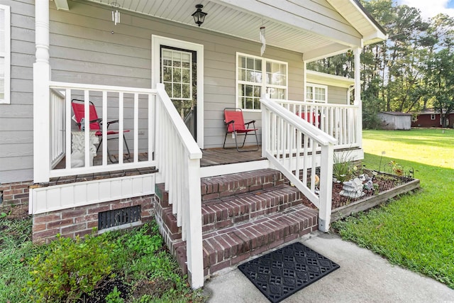 doorway to property featuring a porch and a lawn