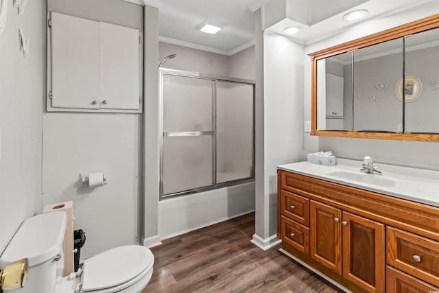 full bathroom with shower / bath combination with glass door, vanity, wood-type flooring, crown molding, and toilet