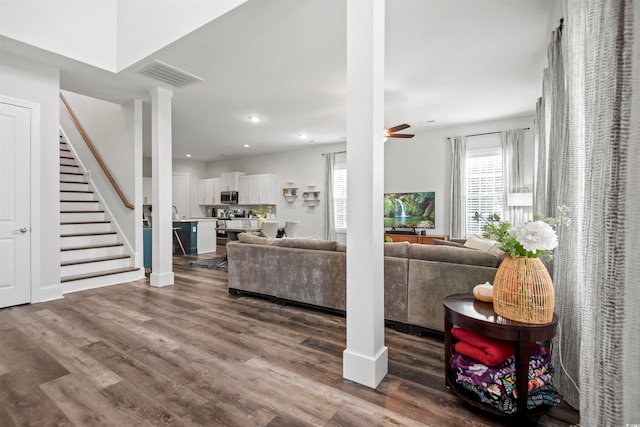 living room featuring ceiling fan, dark hardwood / wood-style floors, and decorative columns