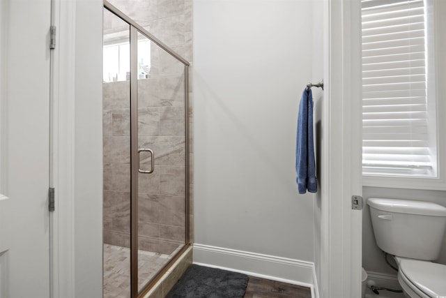 bathroom featuring toilet, an enclosed shower, and wood-type flooring