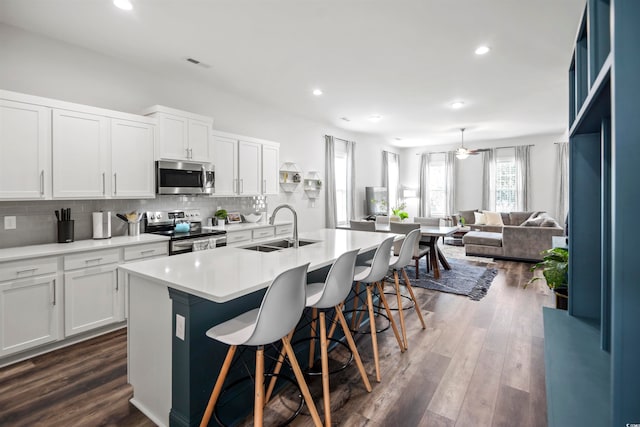 kitchen featuring dark hardwood / wood-style flooring, a center island with sink, white cabinets, sink, and appliances with stainless steel finishes