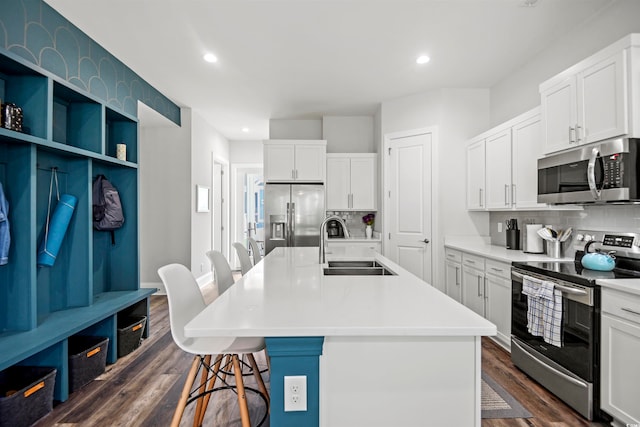 kitchen with a center island with sink, a breakfast bar, appliances with stainless steel finishes, dark hardwood / wood-style floors, and white cabinets