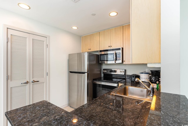 kitchen with light brown cabinetry, appliances with stainless steel finishes, dark stone counters, and sink