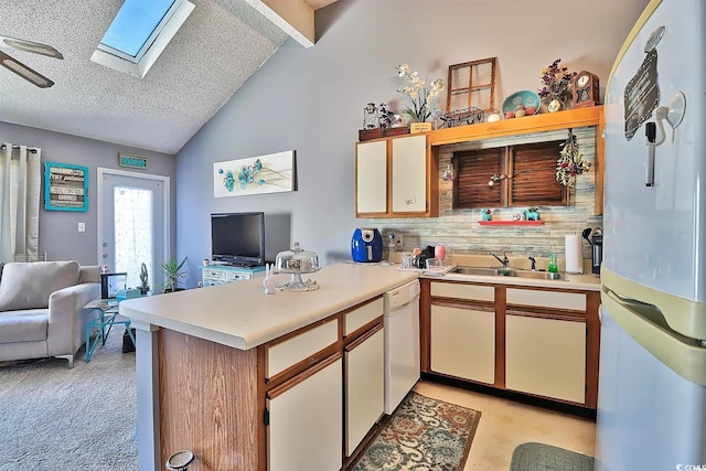 kitchen featuring vaulted ceiling with skylight, a textured ceiling, sink, kitchen peninsula, and white appliances