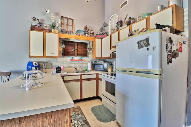 kitchen featuring backsplash, white cabinets, white appliances, and sink