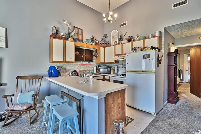 kitchen with pendant lighting, kitchen peninsula, white appliances, backsplash, and a notable chandelier