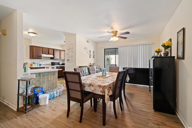 dining space with ceiling fan and light hardwood / wood-style flooring