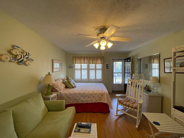 bedroom with light hardwood / wood-style flooring, ceiling fan, and a textured ceiling