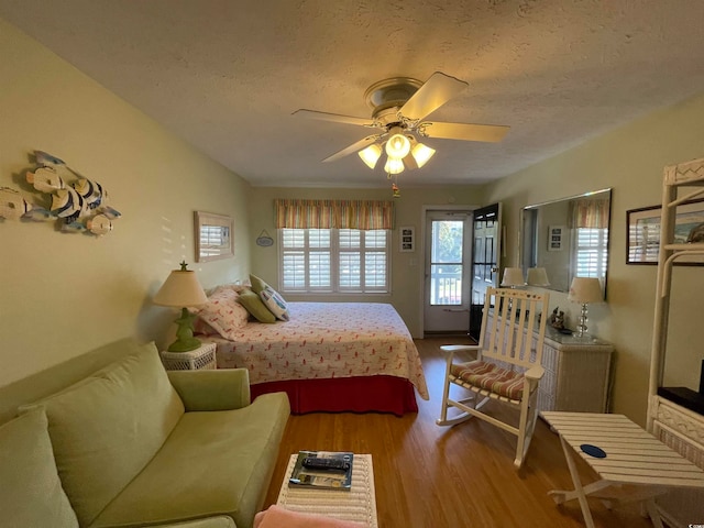 bedroom featuring a textured ceiling, light hardwood / wood-style floors, ceiling fan, and access to exterior