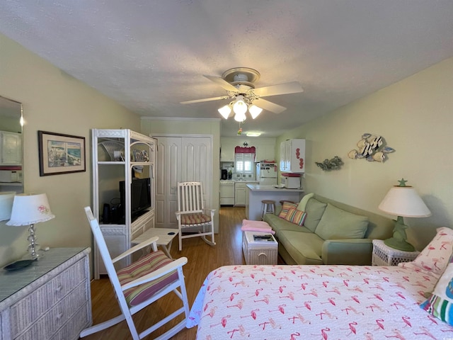 bedroom with white refrigerator, a closet, a textured ceiling, dark wood-type flooring, and ceiling fan