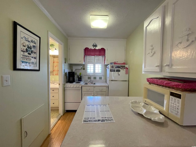 kitchen with light wood-type flooring, sink, white cabinets, white appliances, and ornamental molding