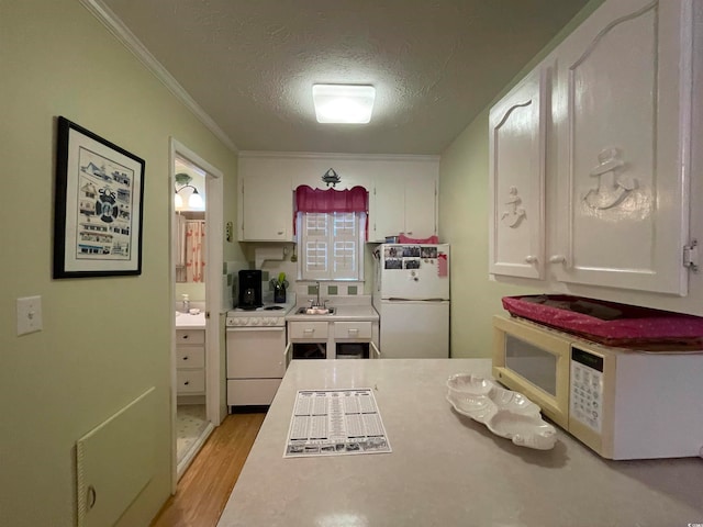 kitchen featuring a textured ceiling, white appliances, ornamental molding, and white cabinets