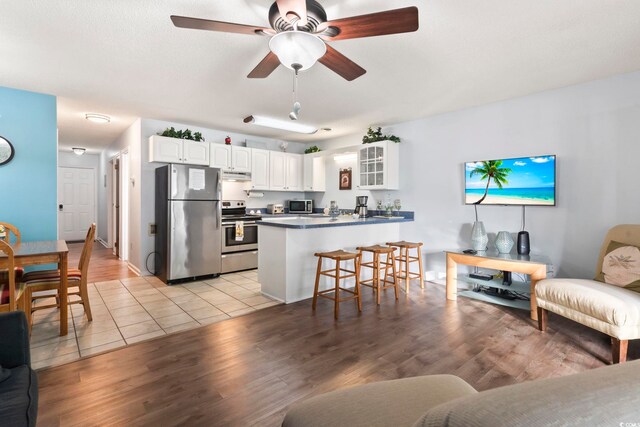 kitchen featuring appliances with stainless steel finishes, kitchen peninsula, light hardwood / wood-style flooring, and white cabinets