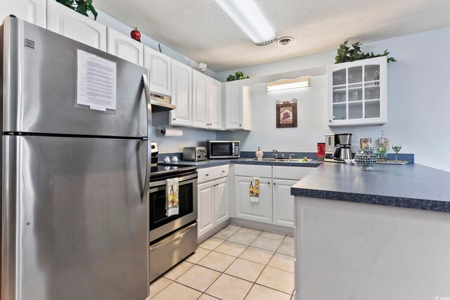 kitchen featuring stainless steel appliances, white cabinetry, a textured ceiling, and ventilation hood