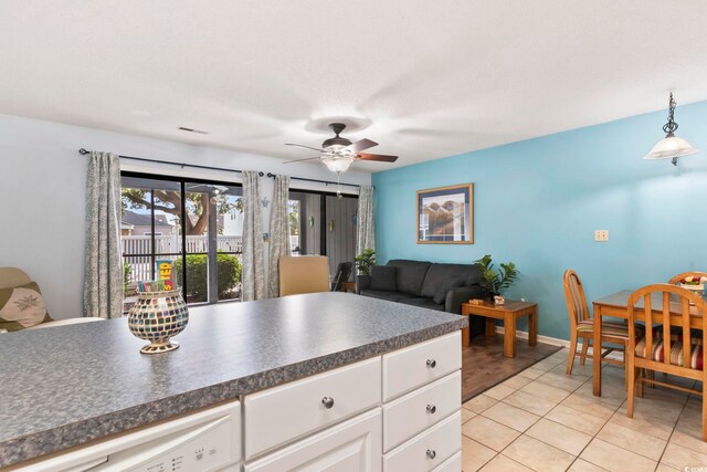 kitchen with hanging light fixtures, light tile patterned floors, white cabinetry, and ceiling fan