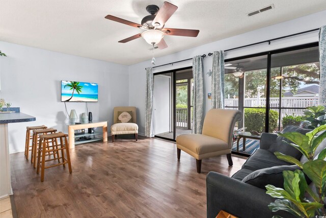 living room featuring ceiling fan, hardwood / wood-style flooring, and a textured ceiling