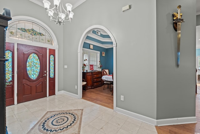 entryway with light tile patterned floors, a notable chandelier, and ornamental molding