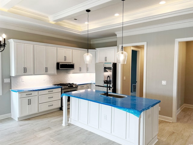 kitchen featuring a center island with sink, ornamental molding, light wood-type flooring, white cabinetry, and appliances with stainless steel finishes