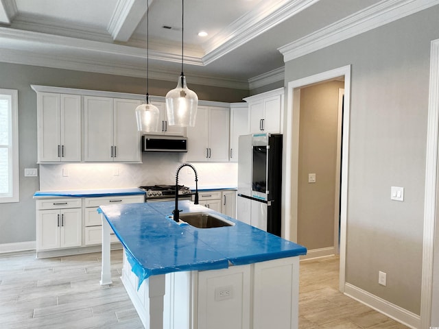 kitchen with stainless steel appliances, a center island with sink, sink, pendant lighting, and white cabinets