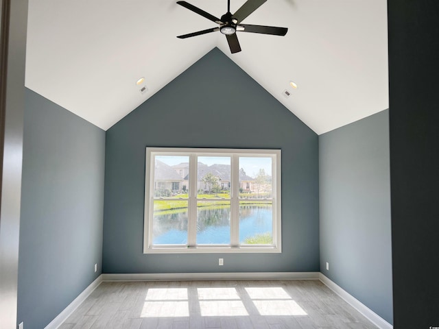 empty room with lofted ceiling, a water view, light wood-type flooring, and ceiling fan