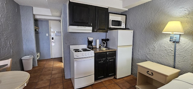 kitchen featuring a textured ceiling, white appliances, dark tile patterned floors, sink, and exhaust hood