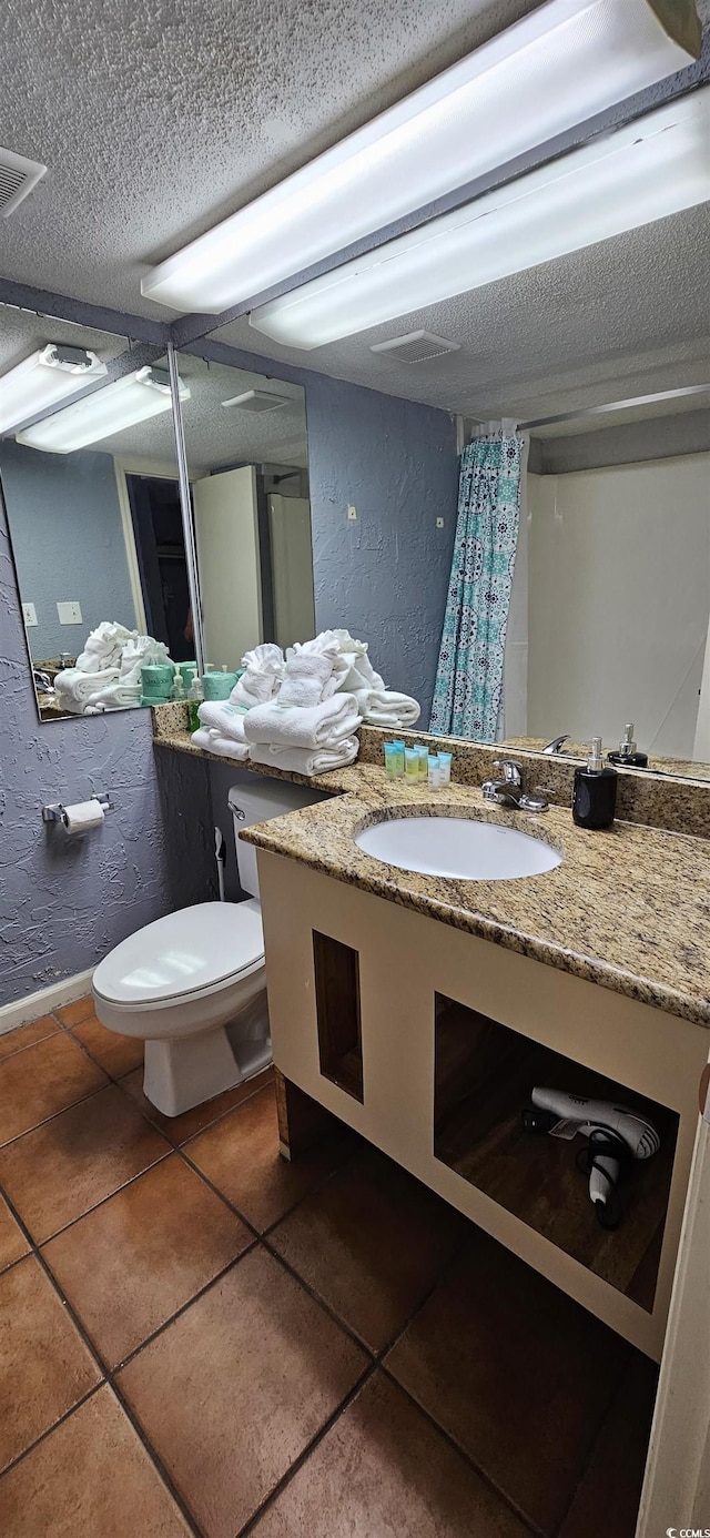 bathroom featuring tile patterned floors, a textured ceiling, toilet, and sink