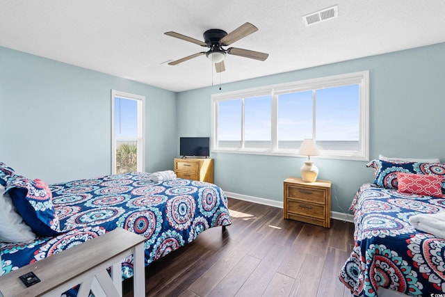 bedroom featuring baseboards, ceiling fan, wood finished floors, and visible vents