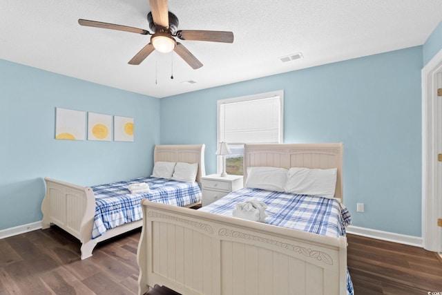 bedroom featuring visible vents, baseboards, a textured ceiling, a ceiling fan, and dark wood finished floors
