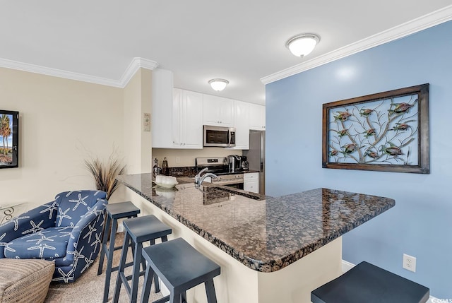 kitchen with white cabinets, stainless steel appliances, crown molding, and kitchen peninsula