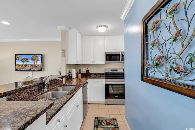 kitchen with sink, white cabinetry, appliances with stainless steel finishes, crown molding, and dark stone countertops