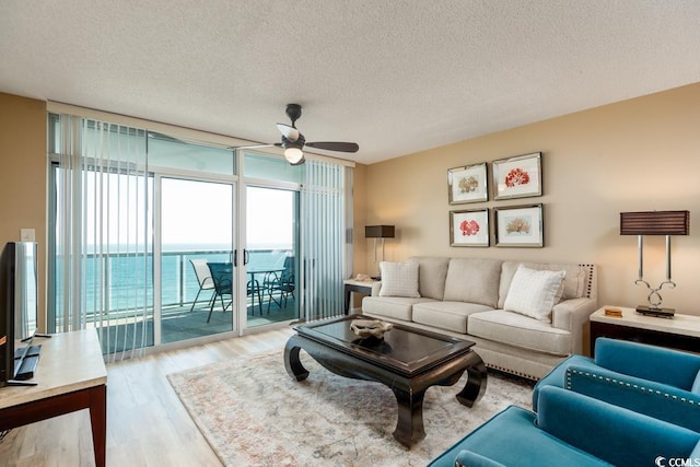 living room with floor to ceiling windows, a textured ceiling, a ceiling fan, and wood finished floors