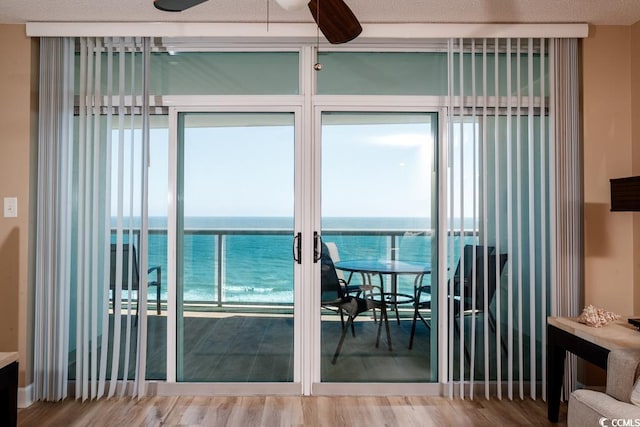 doorway to outside featuring ceiling fan, a water view, and wood finished floors